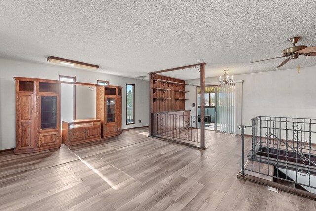 13015 E Mallon Ct, Spokane Valley, WA 99216 - unfurnished living room featuring wood finished floors, a textured ceiling, ceiling fan, and a chandelier