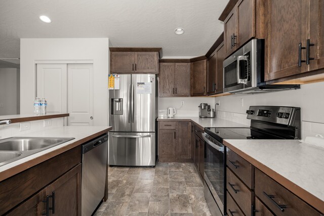 14520 E Everett Ct, Spokane Valley, WA 99216 - kitchen with stainless steel appliances, light countertops, stone finish flooring, dark brown cabinetry, and recessed lighting