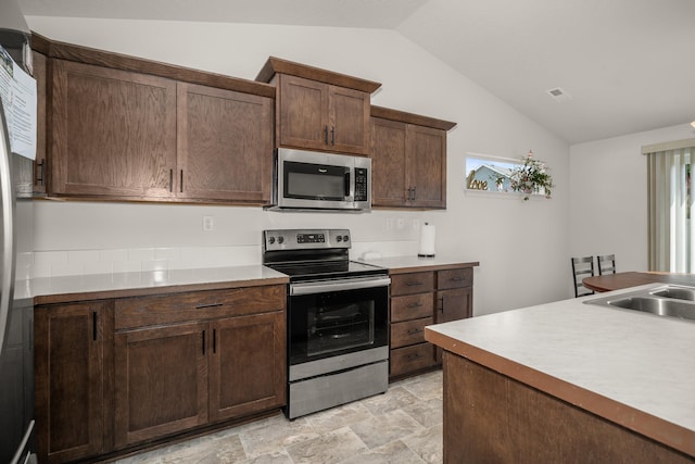 14520 E Everett Ct, Spokane Valley, WA 99216 - kitchen featuring appliances with stainless steel finishes, vaulted ceiling, light countertops, dark brown cabinets, and light stone finish floors