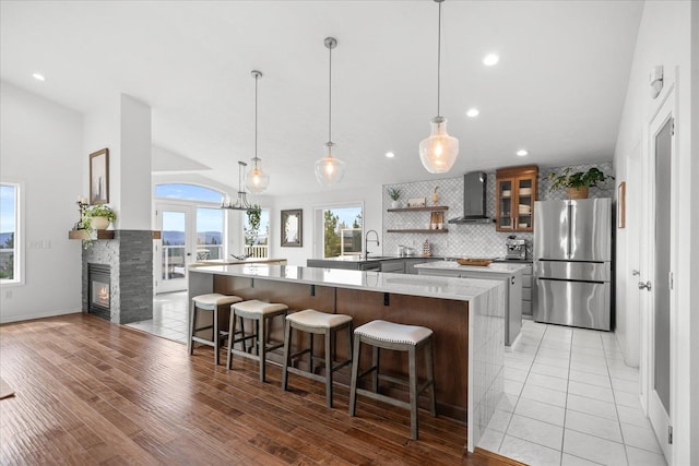 8422 E Sandlewood Ln, Spokane, WA 99217 - kitchen with freestanding refrigerator, wall chimney range hood, vaulted ceiling, decorative backsplash, and glass insert cabinets