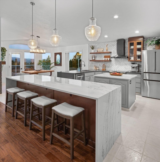 8422 E Sandlewood Ln, Spokane, WA 99217 - kitchen featuring freestanding refrigerator, wall chimney exhaust hood, a large island, tasteful backsplash, and glass insert cabinets