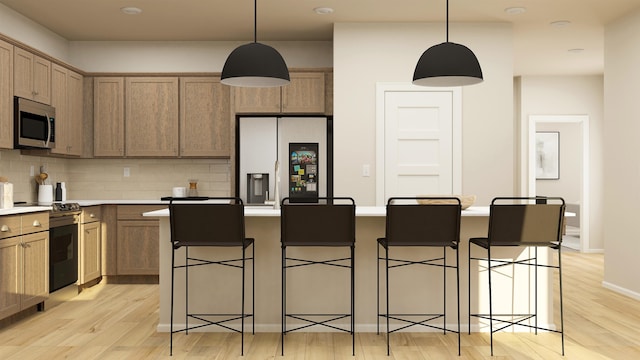 24812 E Hawkstone Loop, Liberty Lake, WA 99019 - kitchen with appliances with stainless steel finishes, light wood finished floors, decorative backsplash, light countertops, and a center island