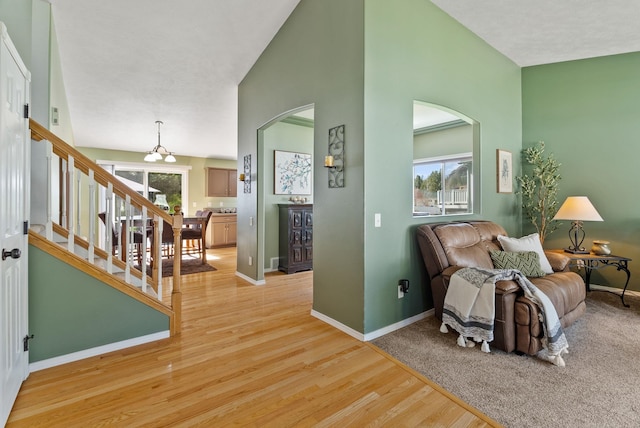 5981 Blackstone Way, Nine Mile Falls, WA 99026 - living area featuring arched walkways, light wood-type flooring, a chandelier, stairs, and high vaulted ceiling