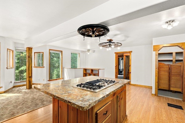 491 Winterfield Rd, Newport, WA 99156 - kitchen with stainless steel gas stovetop, brown cabinets, light wood-style floors, a center island, and ceiling fan