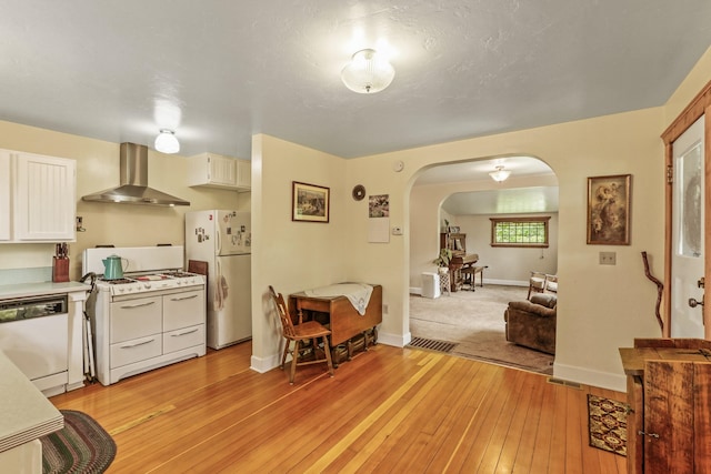11 E Camden Rd, Elk, WA 99009 - kitchen featuring wall chimney range hood, white appliances, arched walkways, light wood-style floors, and light countertops