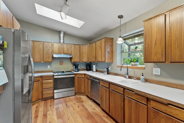 15007 W Willynwood Ln, Nine Mile Falls, WA 99026 - kitchen featuring appliances with stainless steel finishes, a skylight, lofted ceiling, brown cabinets, and under cabinet range hood