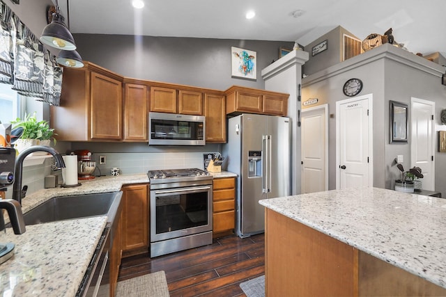 8630 W Campus Dr, Spokane, WA 99224 - kitchen featuring appliances with stainless steel finishes, dark wood-type flooring, tasteful backsplash, light stone countertops, and brown cabinetry