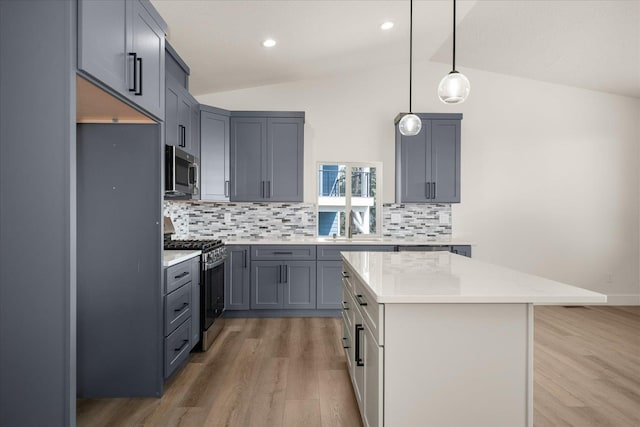 4219 W Tolliver Ct, Spokane, WA 99208 - kitchen with range with gas cooktop, stainless steel microwave, light wood-type flooring, vaulted ceiling, and tasteful backsplash