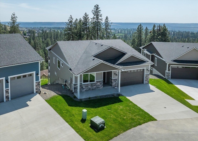 4219 W Tolliver Ct, Spokane, WA 99208 - view of front of house featuring stone siding, concrete driveway, a front yard, covered porch, and roof with shingles