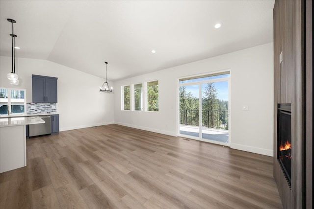 4219 W Tolliver Ct, Spokane, WA 99208 - unfurnished living room with lofted ceiling, a fireplace, a chandelier, light wood-type flooring, and recessed lighting