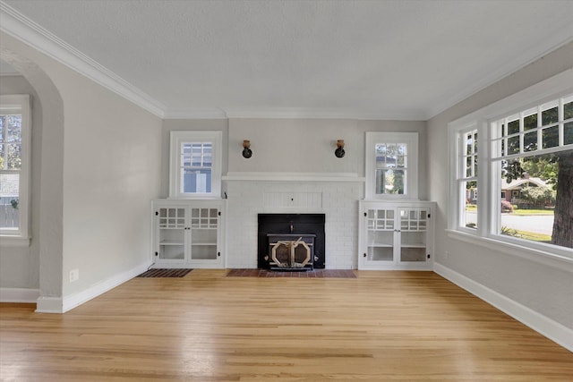 8 W 26th Ave, Spokane, WA 99203 - unfurnished living room with light wood-type flooring, arched walkways, healthy amount of natural light, ornamental molding, and a fireplace