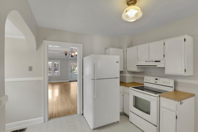 8 W 26th Ave, Spokane, WA 99203 - kitchen with white appliances, under cabinet range hood, white cabinets, a chandelier, and arched walkways