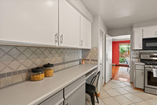 1827 S Arthur St, Spokane, WA 99203 - kitchen with black microwave, gas stove, light countertops, white cabinetry, and decorative backsplash