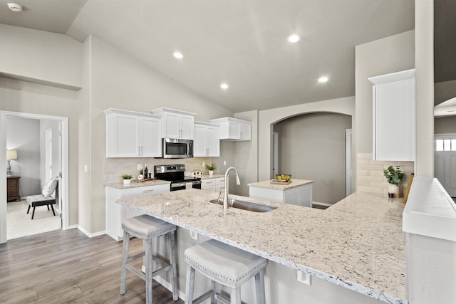 18126 E Barclay Ct Unit 3/4Snowbrush, Spokane Valley, WA 99016 - kitchen featuring appliances with stainless steel finishes, arched walkways, vaulted ceiling, white cabinets, and light wood-type flooring