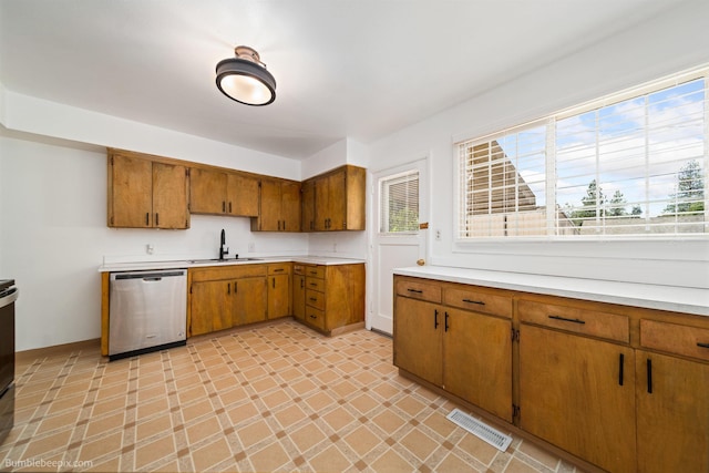1306 W Joseph Ave, Spokane, WA 99205 - kitchen with stainless steel dishwasher, brown cabinetry, light countertops, and light floors