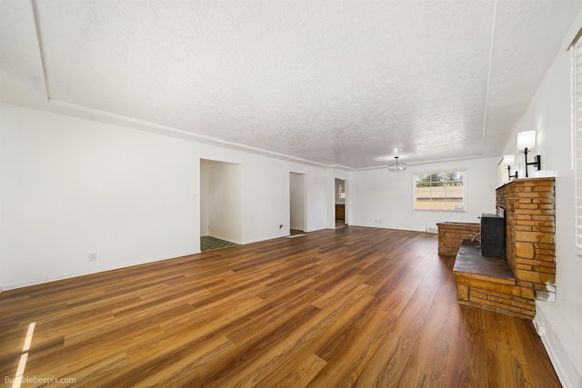 1306 W Joseph Ave, Spokane, WA 99205 - unfurnished living room featuring wood finished floors, a textured ceiling, and a wood stove