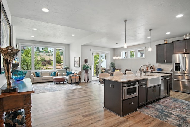 2630 S Fairmont Estates Ct, Greenacres, WA 99016 - kitchen featuring stainless steel appliances, open floor plan, light wood-style flooring, light stone countertops, and a kitchen island with sink