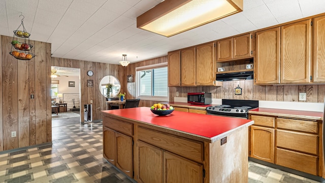 3908 E 26th Ave, Spokane, WA 99223 - kitchen featuring black appliances, wood walls, a center island, under cabinet range hood, and light flooring