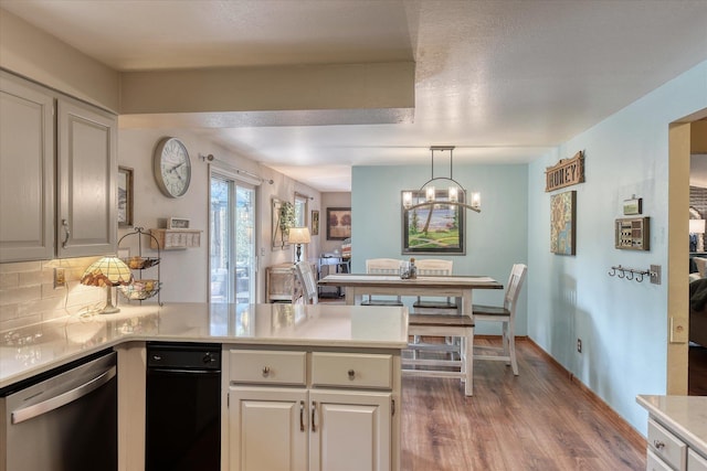 12720 E Kiowa Ct, Spokane Valley, WA 99206 - kitchen with stainless steel dishwasher, a peninsula, light wood-style flooring, light countertops, and decorative backsplash