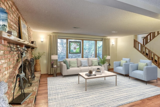 12720 E Kiowa Ct, Spokane Valley, WA 99206 - living room with a textured ceiling, wood finished floors, stairs, and a brick fireplace