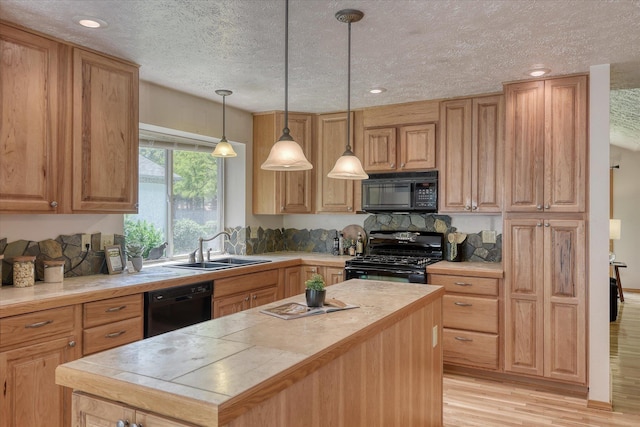 8410 N Pine Meadows Ln, Nine Mile Falls, WA 99026 - kitchen with black appliances, light wood-type flooring, a textured ceiling, a kitchen island, and pendant lighting