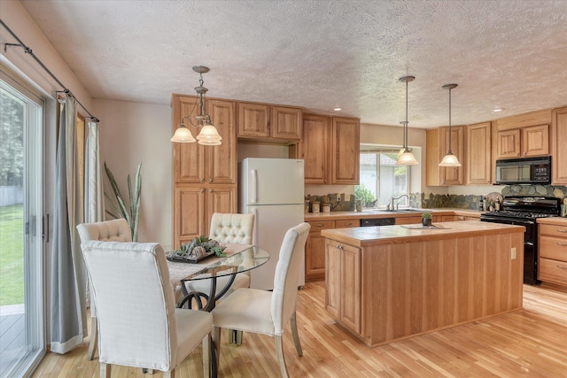 8410 N Pine Meadows Ln, Nine Mile Falls, WA 99026 - kitchen with black appliances, a textured ceiling, light wood finished floors, a center island, and decorative backsplash