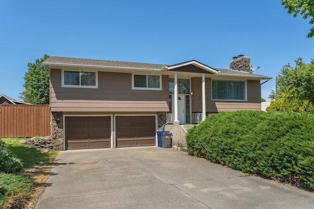 12925 E Valleyway Ave, Spokane Valley, WA 99216 - split foyer home with a chimney, an attached garage, stone siding, and driveway