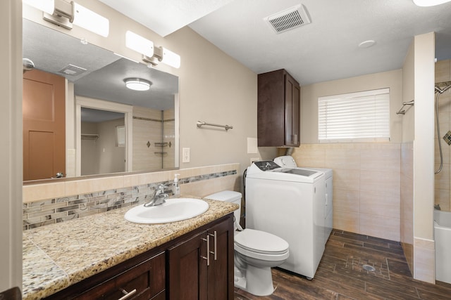 12925 E Valleyway Ave, Spokane Valley, WA 99216 - bathroom featuring tile walls, washer and clothes dryer, vanity, wood finished floors, and tasteful backsplash