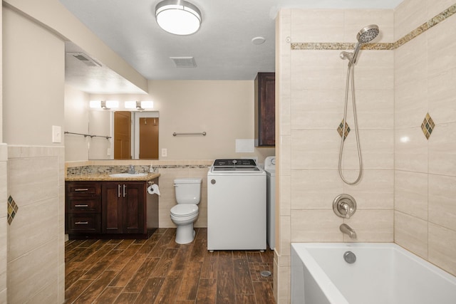 12925 E Valleyway Ave, Spokane Valley, WA 99216 - bathroom with tile walls, vanity, wood finished floors, tub / shower combination, and washer and clothes dryer