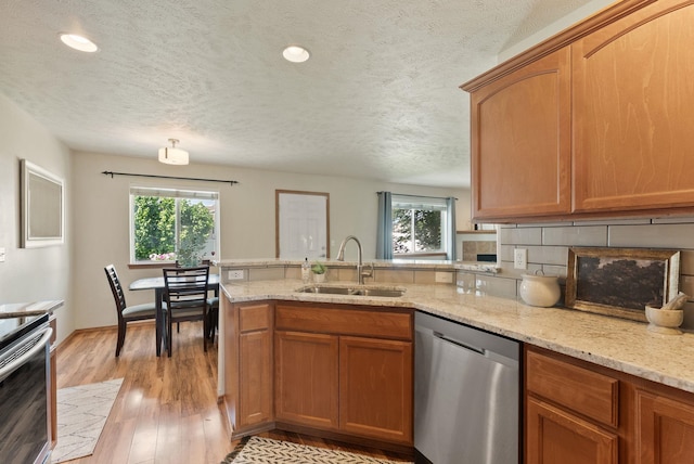 12919 E 39th Ln, Spokane Valley, WA 99206 - kitchen featuring appliances with stainless steel finishes, a peninsula, plenty of natural light, a textured ceiling, and light wood-type flooring