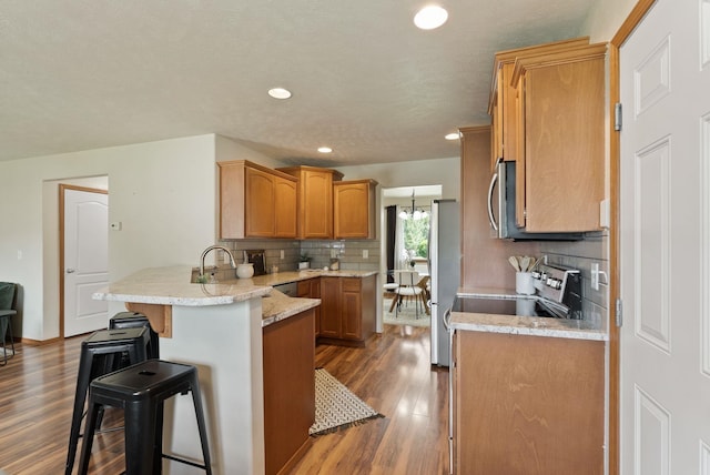 12919 E 39th Ln, Spokane Valley, WA 99206 - kitchen with a peninsula, a breakfast bar area, freestanding refrigerator, dark wood-style floors, and range with electric stovetop