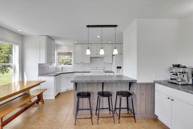 4669 Williams Valley Rd Unit D, Clayton, WA 99110 - kitchen featuring white appliances, white cabinets, a breakfast bar area, dark countertops, and a peninsula