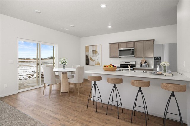 725 E K St, Deer Park, WA 99006 - kitchen with appliances with stainless steel finishes, a kitchen bar, a peninsula, light wood finished floors, and recessed lighting
