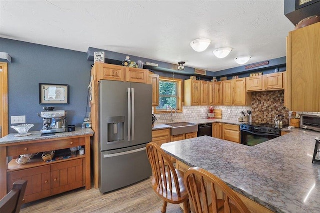 34225 N Arlington Ln, Deer Park, WA 99006 - kitchen with black appliances, backsplash, light wood-style flooring, a peninsula, and a breakfast bar area