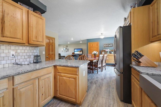 34225 N Arlington Ln, Deer Park, WA 99006 - kitchen with freestanding refrigerator, wood finished floors, tasteful backsplash, and a peninsula