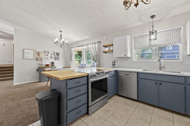 3114 W 20th Ave, Spokane, WA 99224 - kitchen with appliances with stainless steel finishes, a chandelier, a peninsula, tasteful backsplash, and a textured ceiling