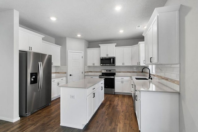 12413 E Dickens Ln, Spokane Valley, WA 99206 - kitchen with appliances with stainless steel finishes, a center island, tasteful backsplash, dark wood-style flooring, and light countertops