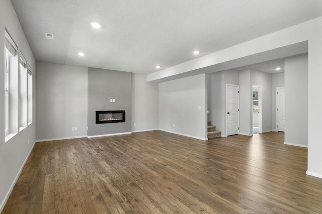 12413 E Dickens Ln, Spokane Valley, WA 99206 - unfurnished living room featuring plenty of natural light, wood finished floors, recessed lighting, stairway, and a glass covered fireplace