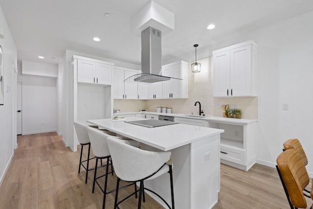 2009 W 9th Ave, Spokane, WA 99204 - kitchen featuring island range hood, a center island, decorative light fixtures, white cabinets, and a breakfast bar area