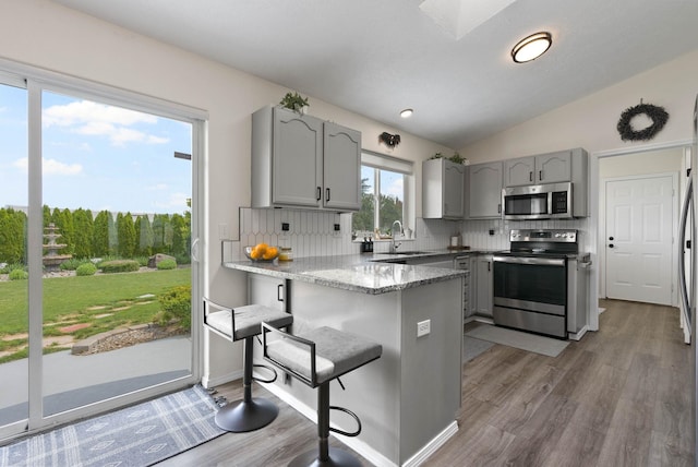 3205 S Mcdonald St, Spokane Valley, WA 99206 - kitchen with appliances with stainless steel finishes, gray cabinetry, a peninsula, decorative backsplash, and lofted ceiling