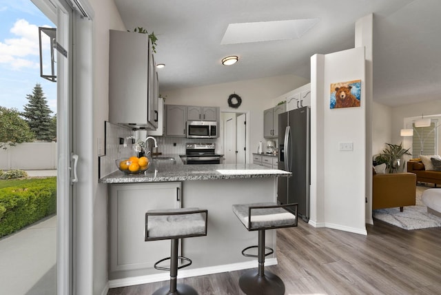 3205 S Mcdonald St, Spokane Valley, WA 99206 - kitchen featuring appliances with stainless steel finishes, gray cabinetry, a peninsula, tasteful backsplash, and wood finished floors