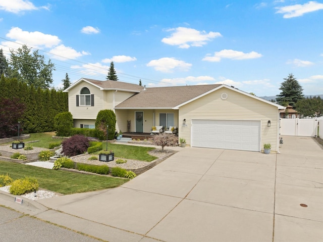3205 S Mcdonald St, Spokane Valley, WA 99206 - tri-level home with a gate, an attached garage, concrete driveway, a porch, and a shingled roof
