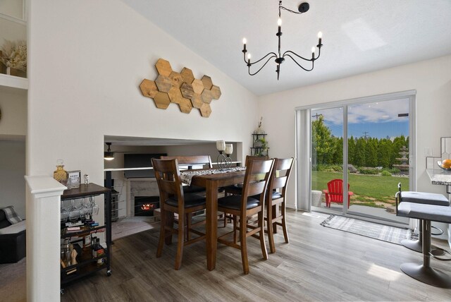 3205 S Mcdonald St, Spokane Valley, WA 99206 - dining space with wood finished floors, a chandelier, vaulted ceiling, and a lit fireplace
