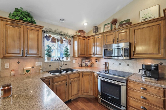 6709 S Moran View St, Spokane, WA 99224 - kitchen featuring appliances with stainless steel finishes, brown cabinetry, decorative backsplash, and lofted ceiling