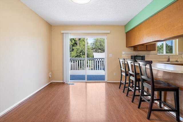 4129 E 32nd Ave, Spokane, WA 99223 - kitchen featuring wood finished floors, healthy amount of natural light, a breakfast bar area, and a textured ceiling