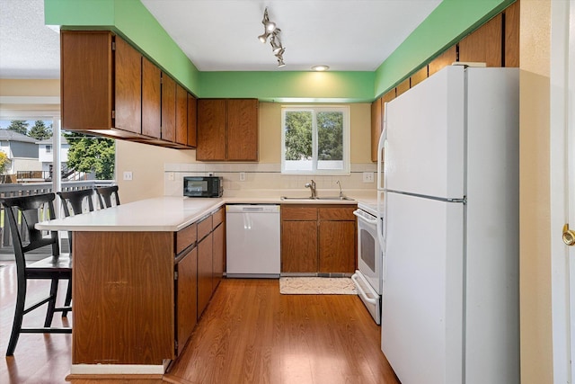 4129 E 32nd Ave, Spokane, WA 99223 - kitchen with white appliances, a peninsula, brown cabinets, light wood-style flooring, and healthy amount of natural light