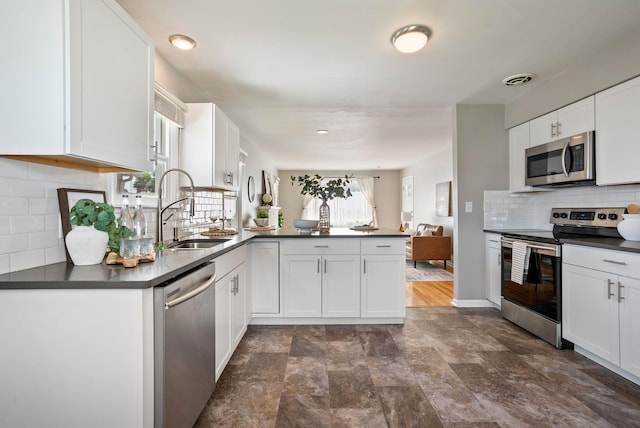 5204 N Maple St, Spokane, WA 99205 - kitchen with appliances with stainless steel finishes, a peninsula, dark countertops, and healthy amount of natural light