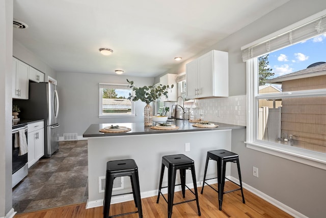 5204 N Maple St, Spokane, WA 99205 - kitchen with stainless steel appliances, a breakfast bar, white cabinets, and a peninsula