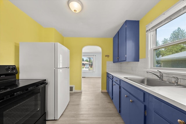 3829 W Broad Ave, Spokane, WA 99205 - kitchen with black range with electric cooktop, blue cabinets, arched walkways, light wood-style floors, and light countertops