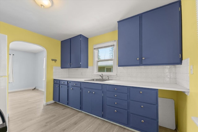 3829 W Broad Ave, Spokane, WA 99205 - kitchen featuring blue cabinetry, arched walkways, light wood-type flooring, decorative backsplash, and light countertops